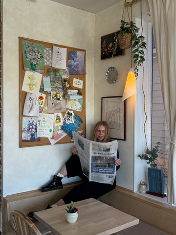 Owner reading newspaper at cozy seating corner inside Art Café SLC creative studio in Salt Lake City