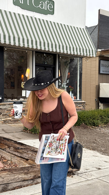 Art Café SLC owner Madi Nilsson outside the Salt Lake City art café holding coffee and artwork